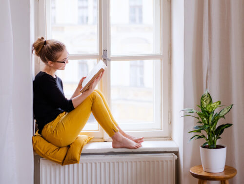 Frau am Fenster liest Materialien der Swiss Harmony Academy